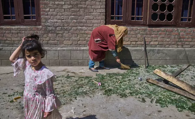 A Kashmiri woman clears shattered glass outside her home after it was damaged in a blast at the house of Asif Sheikh, who officials say is a militant and have blamed for involvement in the deadly attack on tourists in Pahalgam, at Monghama village in Tral, south of Srinagar, Indian controlled Kashmir, Friday, April 25, 2025. (AP Photo/Dar Yasin)