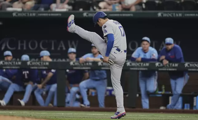 Los Angeles Dodgers' Shohei Ohtani stretches as he walks to first after earning a walk in the eighth inning of a baseball game against the Texas Rangers in Arlington, Texas, Sunday, April 20, 2025. (AP Photo/Tony Gutierrez)