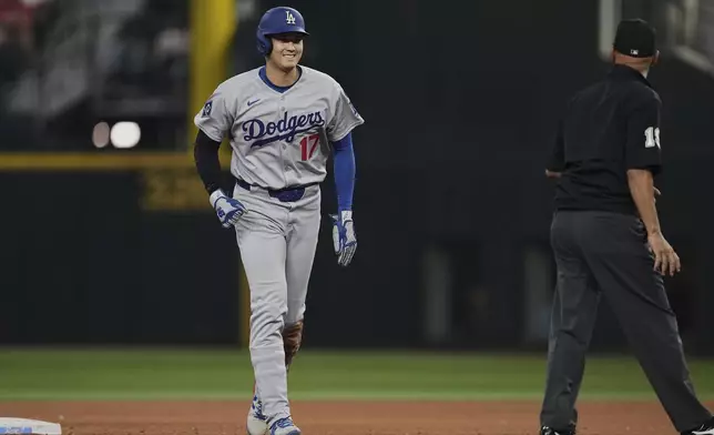 Los Angeles Dodgers' Shohei Ohtani walks to the dugout past umpire Vic Carapazza after a Teoscar Hernandez fly out in the eighth inning of a baseball game against the Texas Rangers in Arlington, Texas, Sunday, April 20, 2025. (AP Photo/Tony Gutierrez)