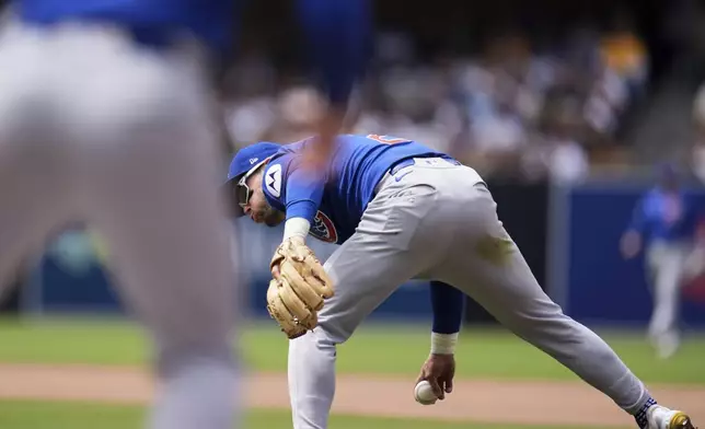 Chicago Cubs second baseman Nico Hoerner tosses the ball to first base between his legs too late as San Diego Padres' Tyler Wade arrives safely for a single during the fifth inning of a baseball game Wednesday, April 16, 2025, in San Diego. (AP Photo/Gregory Bull)