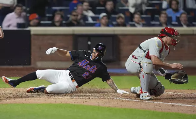 New York Mets' Mark Vientos, left, slides past Philadelphia Phillies catcher J.T. Realmuto, right, to score on a single by Luis Torrens of a baseball game Tuesday, April 22, 2025, in New York. (AP Photo/Frank Franklin II)