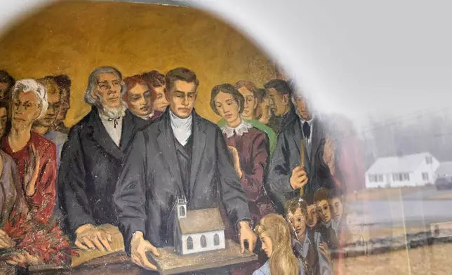 A fresco depicting community members with a model of South Solon Meeting House is seen through a window in the lobby of the building, Sunday, April 6, 2025, in Solon, Maine. (AP Photo/Robert F. Bukaty)