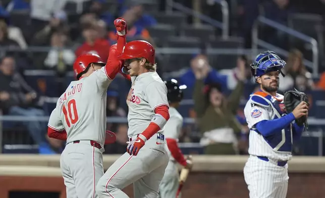 New York Mets catcher Luis Torrens, right, looks away as Philadelphia Phillies' Bryson Stott, center, and J.T. Realmuto celebrate after they scored on a three-run home run by Stott during the ninth inning of a baseball game Monday, April 21, 2025, in New York. (AP Photo/Frank Franklin II)