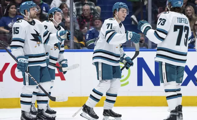 San Jose Sharks' Macklin Celebrini (71) celebrates after his goal against the Vancouver Canucks with teammates Nikolai Kovalenko (15), Luca Cagnoni (42) and Tyler Toffoli (73) during the second period of an NHL hockey game in Vancouver, British Columbia, Monday, April 14, 2025. (Ethan Cairns/The Canadian Press via AP)