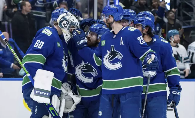 Vancouver Canucks goaltender Nikita Tolopilo (60) celebrates with his teammates after defeating the San Jose Sharks in overtime in an NHL hockey game in Vancouver, British Columbia, Monday, April 14, 2025. (Ethan Cairns/The Canadian Press via AP)