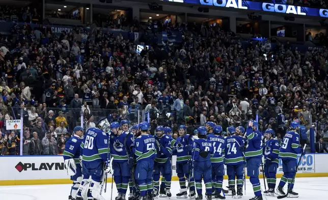 Vancouver Canucks goaltender Nikita Tolopilo (60) celebrates with his teammates after defeating the San Jose Sharks in overtime in an NHL hockey game in Vancouver, British Columbia, Monday, April 14, 2025. (Ethan Cairns/The Canadian Press via AP)