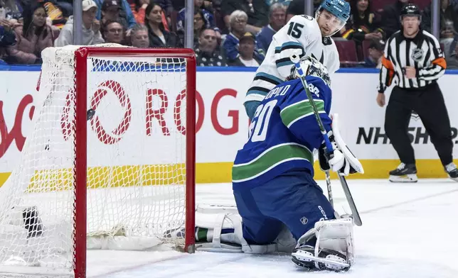 San Jose Sharks' Nikolai Kovalenko (15) watches as Macklin Celebrini, not seen, scores on Vancouver Canucks goaltender Nikita Tolopilo (60) during the second period of an NHL hockey game in Vancouver, British Columbia, Monday, April 14, 2025. (Ethan Cairns/The Canadian Press via AP)