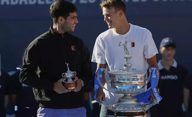 Spain's Carlos Alcaraz, left and the winner Denmark's Holger Rune stand on the podium after the ATP Barcelona Open tennis final in Barcelona, Spain, Sunday, April 20, 2025. AP Photo/Joan Monfort)