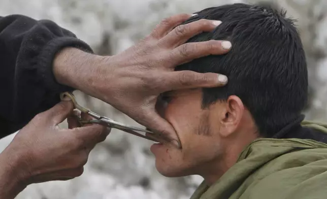 FILE -An Afghan street barber man, left, trims the mustache of a customer, as snow is seen the back ground in Kabul, Afghanistan, Feb. 9, 2012. (AP Photo/Musadeq Sadeq, File)