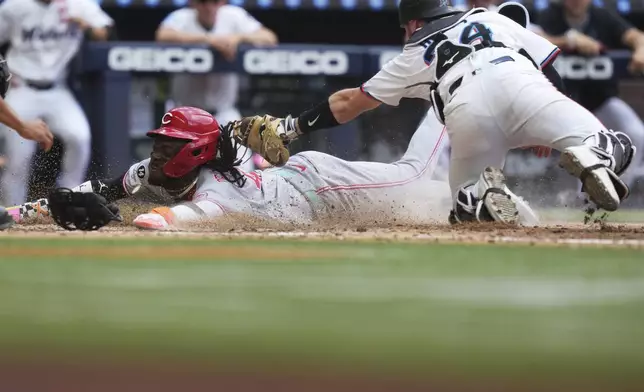 Cincinnati Reds' Elly De La Cruz, left, beats the tag by Miami Marlins catcher Liam Hicks (34) to score during the eighth inning of a baseball game, Wednesday, April 23, 2025, in Miami. (AP Photo/Lynne Sladky)