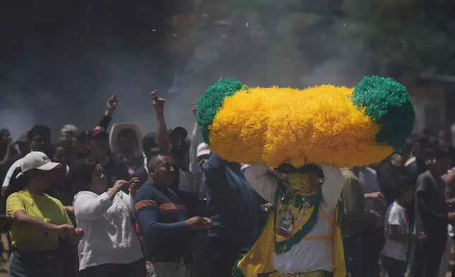 A reveler, known as a sayon, runs with a tissue paper hat as onlookers throw lit matches at him during Easter celebrations in Tetela del Volcan, Mexico, Sunday, April 20, 2025. (AP Photo/Eduardo Verdugo)