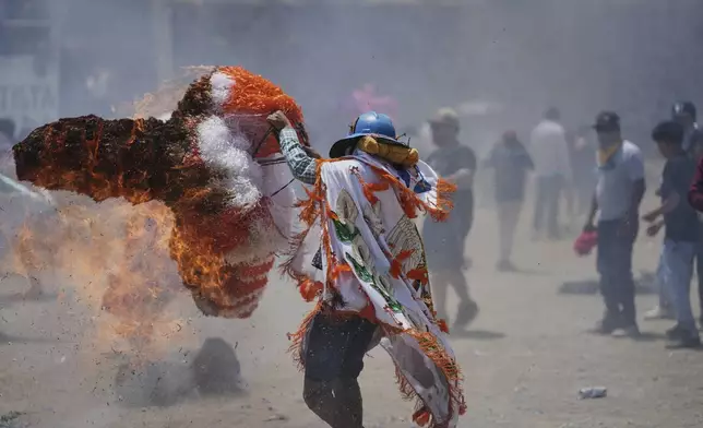 A reveler, known as a sayon, tries to put out a fire he started on his tissue paper hat as part of Easter celebrations in Tetela del Volcan, Mexico, Sunday, April 20, 2025. (AP Photo/Eduardo Verdugo)
