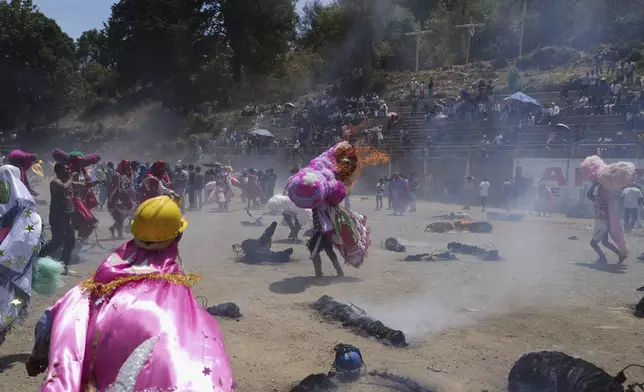 A reveler, known as a sayon, tries to put out a fire he started on his tissue paper hat as part of Easter celebrations in Tetela del Volcan, Mexico, Sunday, April 20, 2025. (AP Photo/Eduardo Verdugo)