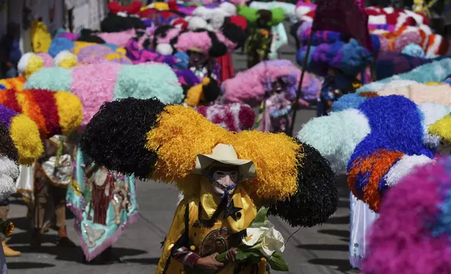 Revelers, known as sayones, wear tissue paper hats during an Easter celebration, in Tetela del Volcan, Mexico, Sunday, April 20, 2025. (AP Photo/Eduardo Verdugo)