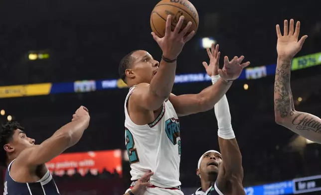 Memphis Grizzlies guard Desmond Bane, center, shoots the ball past Dallas Mavericks defenders during the first half of an NBA play-in tournament basketball game Friday, April 18, 2025, in Memphis, Tenn. (AP Photo/George Walker IV)
