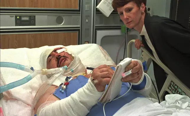 FILE - Randy Ledger, who was severely injured by the bomb blast at the Alfred P. Murrah Federal Building, writes a note from his bed in the intensive care unit of Presbyterian Hospital in Oklahoma City on April 20, 1995, as his sister, Linda Halford, watches. (AP Photo/Pat Sullivan, File)