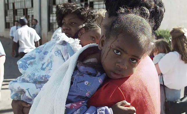FILE - A woman comforts an injured child following an explosion at the Alfred P. Murrah Federal Building in Oklahoma City on April 19, 1995. (AP Photo/David Longstreath, File)