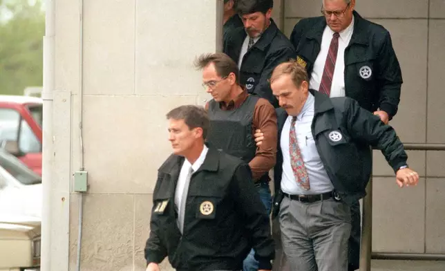 FILE - Terry Nichols, wearing a bullet-proof vest, is escorted by U.S. marshals as he leaves the federal courthouse in Wichita, Kansas, on April 26, 1995. (AP Photo/Steve Rasmussen, File)