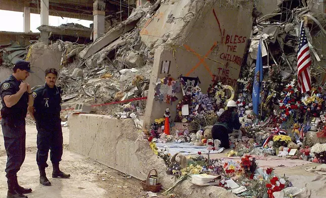FILE - Officials stand near the Alfred P. Murrah Federal Building as workers place flowers and memorial items at the scene of the explosion in Oklahoma City on May 5, 1995. (AP Photo/J. Pat Carter, File)
