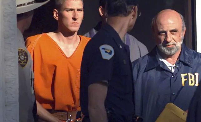 FILE - Timothy James McVeigh, identified as a suspect in the bombing of the Oklahoma City Federal building, is lead out of the Noble County Courthouse in Perry, Okla., by state and federal law enforcement officials on April 21, 1995. (AP Photo/John Gaps III, File)