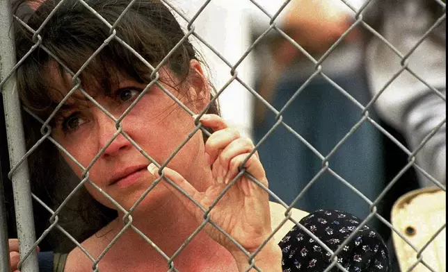 FILE - Karen Ellison looks through a chain link fence at a memorial service for rescue workers and volunteers at the Alfred P. Murrah Federal Building in Oklahoma City on May 5, 1995. (AP Photo J. Pat Carter, File)