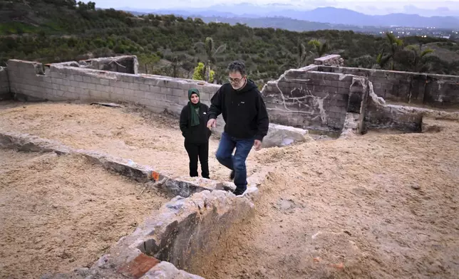 Hatim Naim and his wife Samah walk in the ruins of their property which burned in the Mountain Fire Wednesday, April 16, 2025, in Somis, Calif. (AP Photo/Wally Skalij)