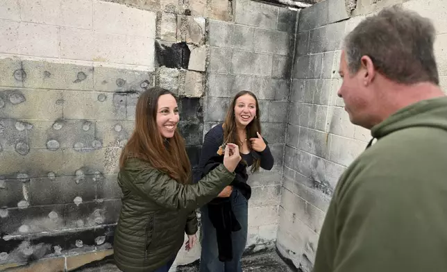 Rachel McNett, left, finds a piece of her old passport as daughter Teagan and husband Keith look on as they visit there house that burned in the Mountain Fire Wednesday, April 16, 2025, in Camarillo, Calif. (AP Photo/Wally Skalij)