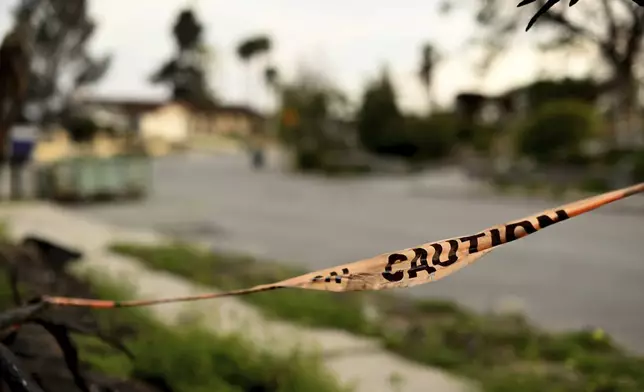 Caution tape hangs on a branch along Old Coach Drive after the Mountain Fire burned through the area Wednesday, April 16, 2025, in Camarillo, Calif. (AP Photo/Wally Skalij)