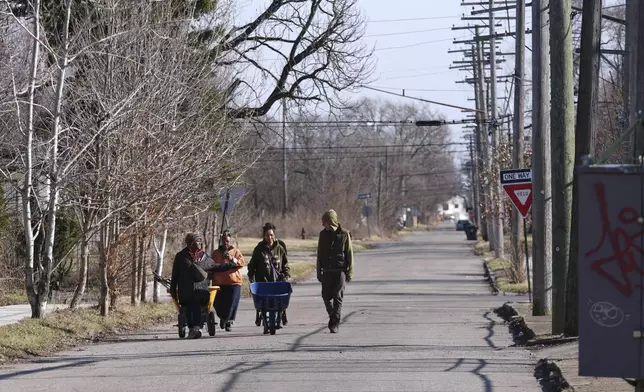 Robyn Redding, from left, Jozie Bullard, Gianna Holliday and Andrew "Birch" Kemp walk to a Arboretum Detroit parcel in Detroit, Friday, March 21, 2025. (AP Photo/Paul Sancya)