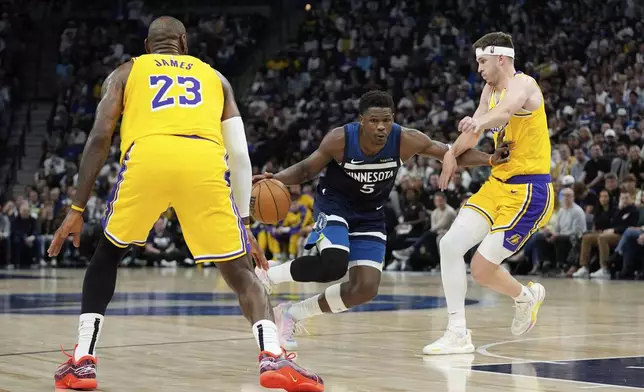 Minnesota Timberwolves guard Anthony Edwards (5) works toward the basket as Los Angeles Lakers forward LeBron James (23) and guard Austin Reaves (15) defend during the first half of Game 3 of an NBA basketball first-round playoff series, Friday, April 25, 2025, in Minneapolis. (AP Photo/Abbie Parr)
