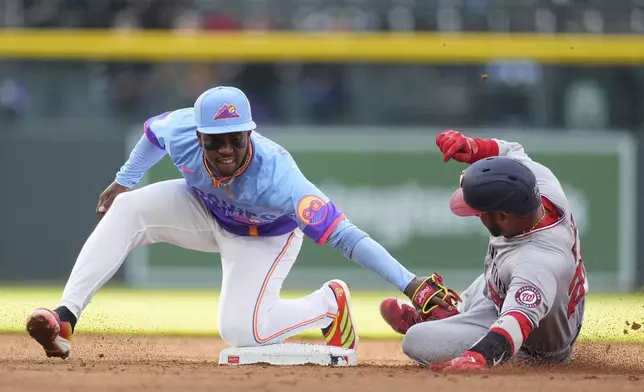 Colorado Rockies second baseman Adael Amador, left, tags out Washington Nationals' Keibert Ruiz at second base as he tries to stretch a single into a double in the third inning of Game 2 of a split baseball doubleheader Sunday, April 20, 2025, in Denver. (AP Photo/David Zalubowski)