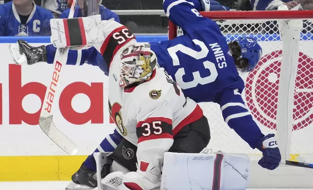 Toronto Maple Leafs' Matthew Knies (23) falls over Ottawa Senators' goaltender Linus Ullmark (35) during third period NHL playoff action in Toronto, on Sunday, April 20, 2025. (Frank Gunn/The Canadian Press via AP)