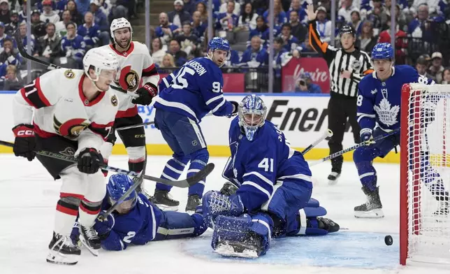 Ottawa Senators' Ridly Greig (71) scores a goal on Toronto Maple Leafs' goaltender Anthony Stolarz (41) as Simon Benoit (2) tries to defend during third period NHL playoff action in Toronto, on Sunday, April 20, 2025. (Frank Gunn/The Canadian Press via AP)