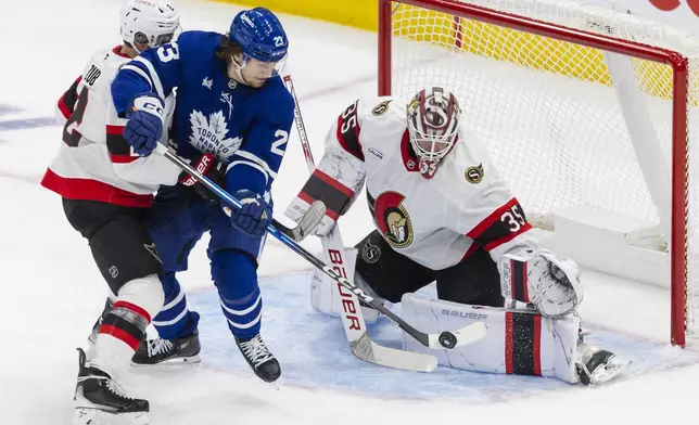 Ottawa Senators‚ Linus Ullmark (35) kicks away a puck while Toronto Maple Leafs‚ Matthew Knies (23) and Ottawa Senators‚ Artem Zub (2) battle in front of the net during second period NHL playoff action in Toronto, on Sunday, April 20, 2025. (Nick Iwanyshyn/The Canadian Press via AP)