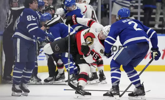 Ottawa Senators' Matthew Highmore (15) and Toronto Maple Leafs' Simon Benoit (2) rough it up during third period NHL playoff action in Toronto, on Sunday, April 20, 2025. (Frank Gunn/The Canadian Press via AP)
