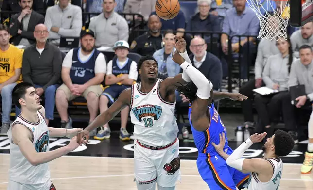 Oklahoma City Thunder guard Luguentz Dort (5) shoots against Memphis Grizzlies forward Jaren Jackson Jr. (13) and guard Scotty Pippen Jr. (1) as center Zach Edey (14) moves for position in the second half of Game 3 of an NBA first-round playoff series Thursday, April 24, 2025, in Memphis, Tenn. (AP Photo/Brandon Dill)