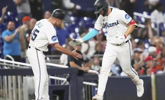 Miami Marlins' Eric Wagaman, right, greets the third base coach after hitting a solo home run during the fifth inning of a baseball game against the Cincinnati Reds, Monday, April 21, 2025, in Miami. (AP Photo/Lynne Sladky)