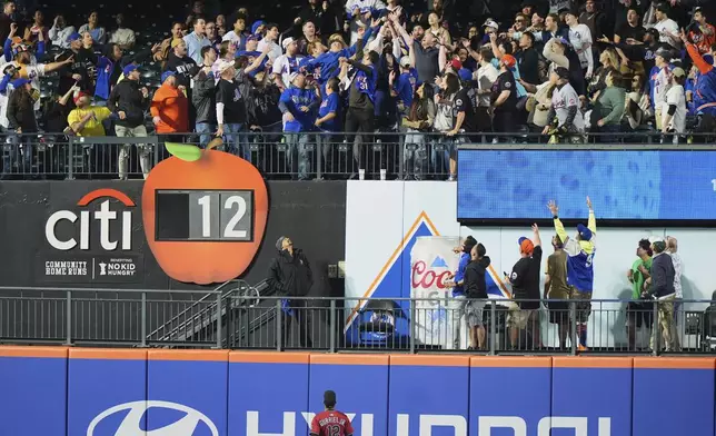 Arizona Diamondbacks outfielder Lourdes Gurriel Jr. (12) watches as fans reach for a ball hit by New York Mets' Starling Marte for a two-run home run during the third inning of a baseball game Tuesday, April 29, 2025, in New York. (AP Photo/Frank Franklin II)