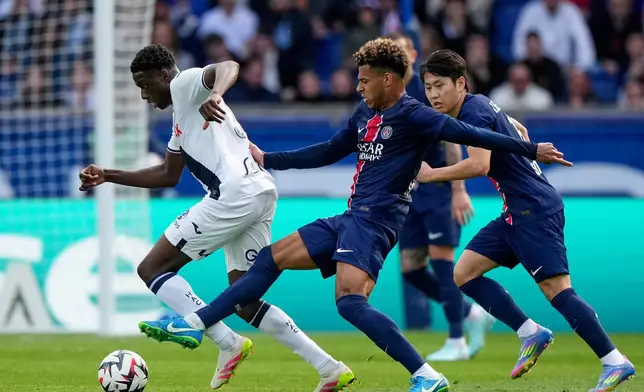 PSG's Desire Doue, center, challenges for the ball with Le Havre's Gautier Lloris, left, during the French League One soccer match between Paris Saint-Germain and Le Havre at the Parc des Princes stadium in Paris, Saturday, April 19, 2025. (AP Photo/Michel Euler)