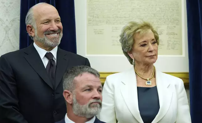Commerce Secretary Howard Lutnick and Education Secretary Linda McMahon watch as President Donald Trump speaks with reporters in the Oval Office of the White House, Wednesday, April 23, 2025, in Washington. (AP Photo/Alex Brandon)