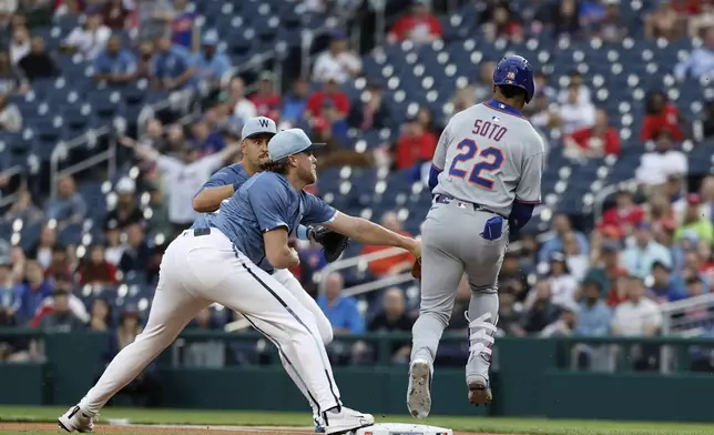 New York Mets' Juan Soto (22) reaches first base and collides with Washington Nationals pitcher Jake Irvin, front left, on a fielding error by first baseman Nathaniel Lowe, back left, during the first inning of a baseball game in Washington, Friday, April 25, 2025. (AP Photo/Terrance Williams)