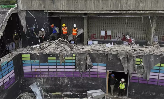 Rescue workers stand at site of the Jet Set nightclub days after its roof collapsed during a concert, killing more than 200 people in Santo Domingo, Dominican Republic, Thursday, April 10, 2025. (AP Photo/Matias Delacroix)