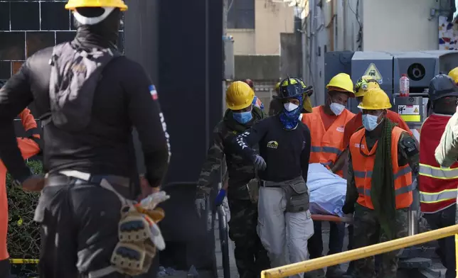 Rescue workers carry the recovered body of a victim who died when the roof collapsed two nights prior at the Jet Set nightclub during a merengue concert, in Santo Domingo, Dominican Republic, Wednesday, April 9, 2025. (AP Photo/Ricardo Hernandez)