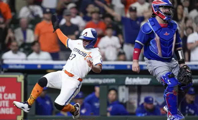 Houston Astros' Jose Altuve, left, slides to score on a two-run double by teammate Isaac Paredes during the fifth inning of a baseball game against the Toronto Blue Jays, Monday, April 21, 2025, in Houston. (AP Photo/Eric Christian Smith)