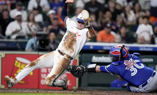 against the Houston Astros' Zach Dezenzo (9) avoids a tag by Toronto Blue Jays catcher Alejandro Kirk, right, to score on an RBI single by teammate Yordan Alvarez during the seventh inning of a baseball game Monday, April 21, 2025, in Houston. (AP Photo/Eric Christian Smith)