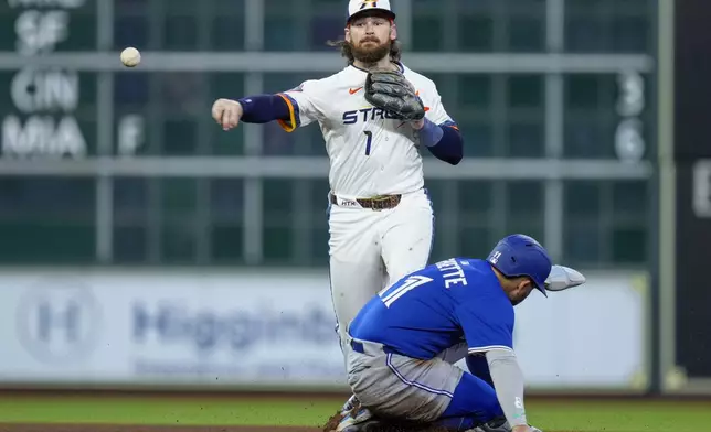 Houston Astros second baseman Brendan Rodgers (1) completes a double play over Toronto Blue Jays' Bo Bichette, bottom, during the sixth inning of a baseball game Monday, April 21, 2025, in Houston. (AP Photo/Eric Christian Smith)