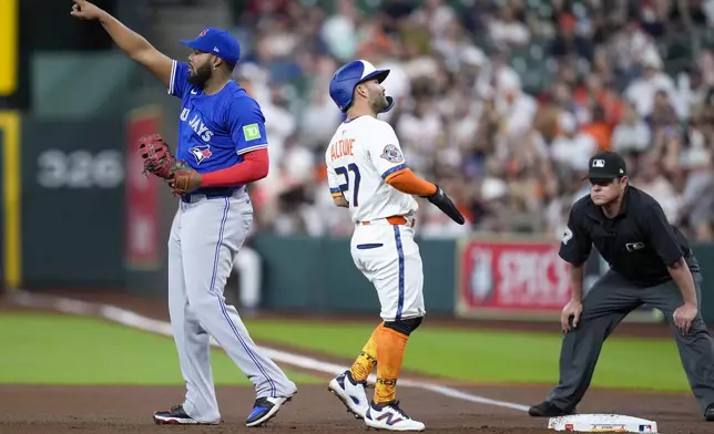 Toronto Blue Jays first baseman Vladimir Guerrero Jr., left, points to left fielder Alan Roden after Guerrero Jr. completed a double play off Houston Astros' Jose Altuve, center, during the first inning of a baseball game Monday, April 21, 2025, in Houston. (AP Photo/Eric Christian Smith)