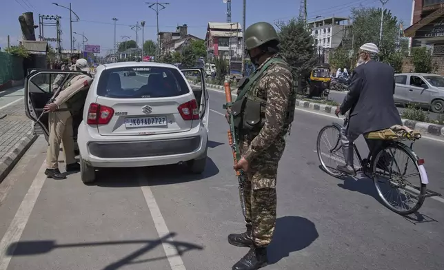 A policeman, left, checks a vehicle as paramilitary soldiers stand guard at a temporary checkpoint in Srinagar, Indian controlled Kashmir, Wednesday, April 30, 2025. (AP Photo/Dar Yasin)