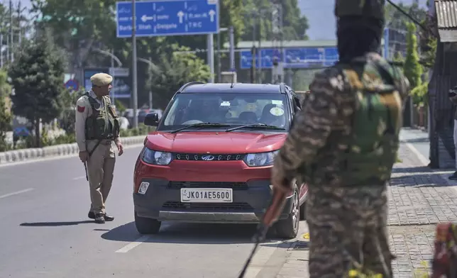 Indian policeman left, questions a driver of vehicle before checking his vehicle at a temporary checkpoint in Srinagar, Indian controlled Kashmir, Wednesday, April 30, 2025. (AP Photo/Dar Yasin)