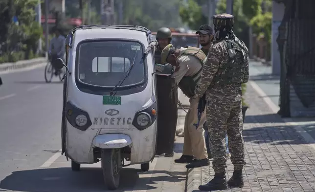 A policeman, checks an auto rickshaw as paramilitary soldiers stand guard at a temporary checkpoint in Srinagar, Indian controlled Kashmir, Wednesday, April 30, 2025. (AP Photo/Dar Yasin)